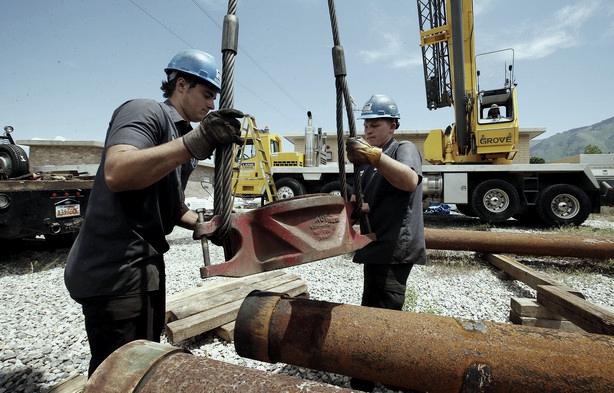 Workers moving well shaft coupling.